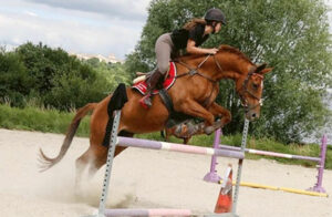 Adolescente sautant un obstacle pendant le séjour équitation en Tarn-et-Garonne