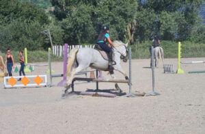 Enfant effectuant un saut d’obstacle pendant la colonie équitation