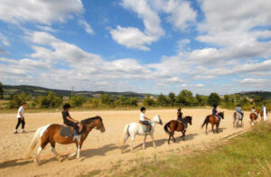 enfant en reprise à cheval dans la carrière de la colonie équitation